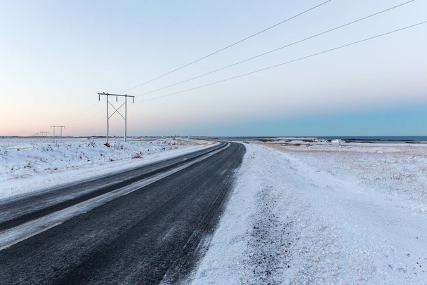An empty road and power lines in winter Iceland - 写真・画像