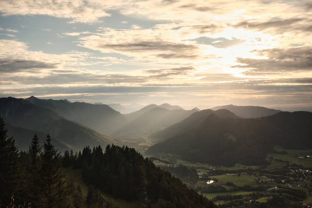 A landscape of hills covered in trees under the sunlight and a cloudy sky in the morning - Foto, Bild