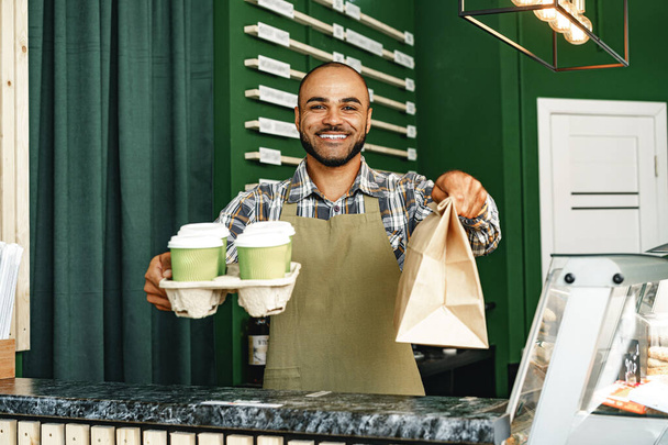 Portrait of a mixed race young man barista in coffee shop - Fotó, kép
