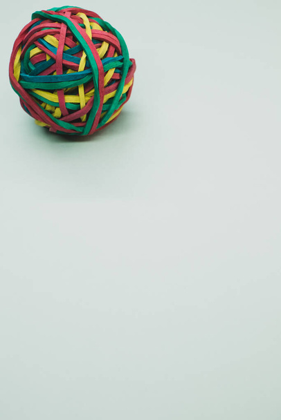A vertical shot of a rubber ball made out of rubber bands isolated on a white background - Фото, изображение