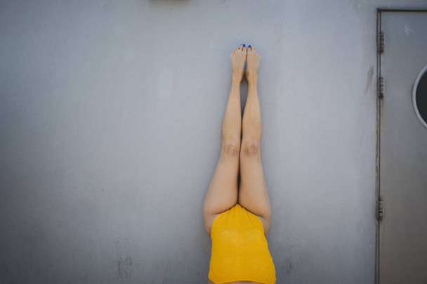 A closeup shot of woman legs with yellow swimsuit leaned on a wall - Zdjęcie, obraz