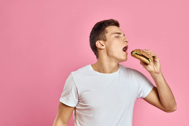 mies iso hampurilainen vaaleanpunainen tausta kalorit pikaruokaa rajattu näkymä Kopioi tilaa lähikuva - Valokuva, kuva