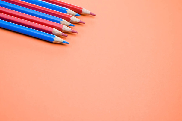 A high angle shot of red and blue pencils on a red surface - Fotó, kép