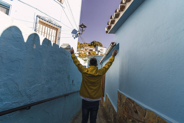 A male wearing a yellow jacket while standing in a narrow alley - Fotó, kép