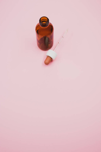 An open dropper bottle on a light pink background - Photo, Image