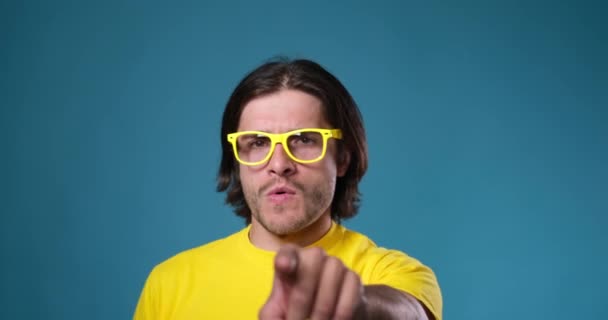 Mężczyzna w żółtych okularach tańczy na niebieskim tle - Materiał filmowy, wideo