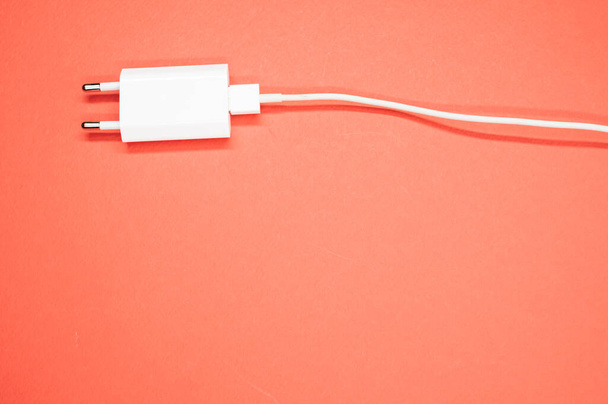 A top view of a white smartphone charger on a peach-colored surface - Foto, Imagen