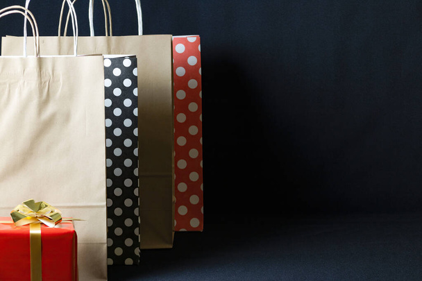 A polka dots and brown eco paper bags and Christmas gift boxes with copy space isolated on a dark background - Photo, image