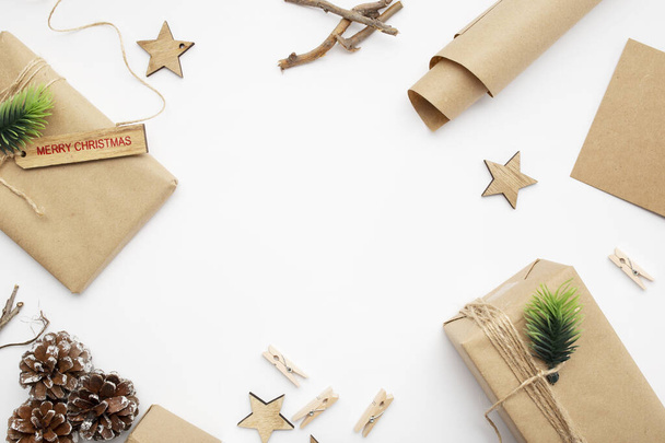 Μια κορυφαία άποψη του τυλιγμένα δώρα, κλαδιά σύκου, κουκουνάρια, Καλά Χριστούγεννα ετικέτα με αντίγραφο χώρο που απομονώνονται σε λευκό φόντο - Φωτογραφία, εικόνα