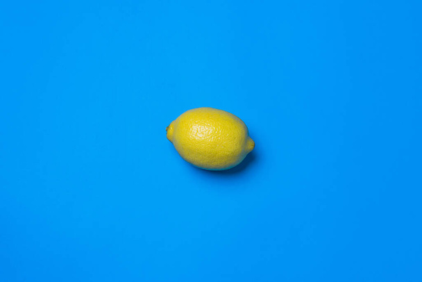 A top view of a lemon on blue background with an empty space for a text - Photo, image
