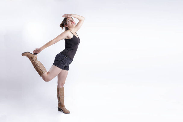A fashion woman wearing top, short and boots posing in a white studio - Fotoğraf, Görsel