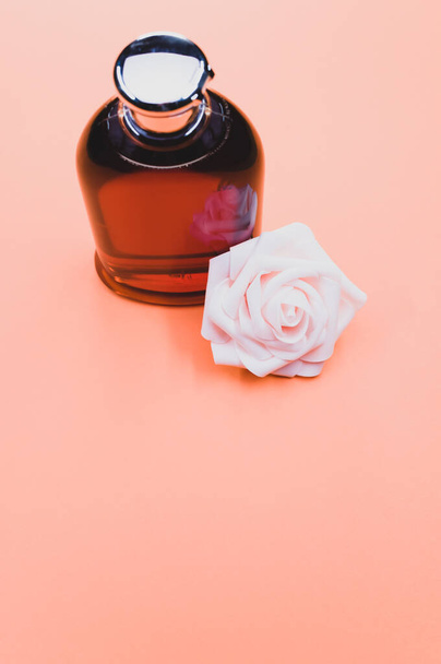 A rose perfume bottle and a rose on an orange background - Photo, image