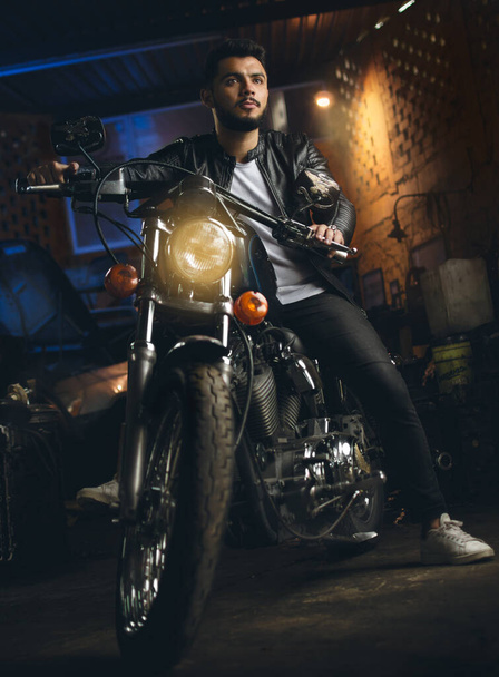 A male sitting on a motorcycle in his garage - Foto, Imagem