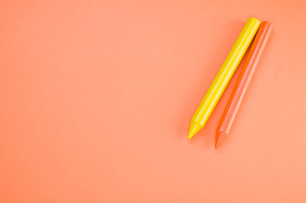 A high angle shot of two crayons on an orange surface - Zdjęcie, obraz