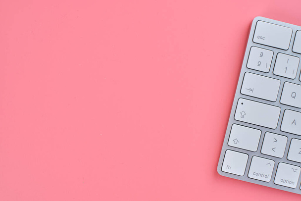 A top view of a pink background with a keyboard and copy space - Foto, afbeelding