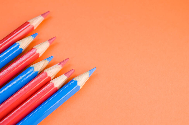 A high angle shot of red and blue pencils on a red surface - Photo, image