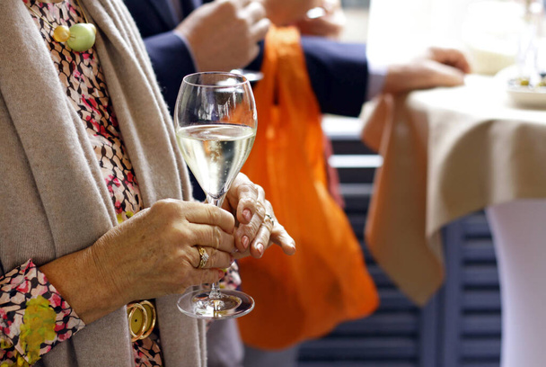 Životní styl bohatých - seniorka držící sklenici šampaňského na akci - Fotografie, Obrázek
