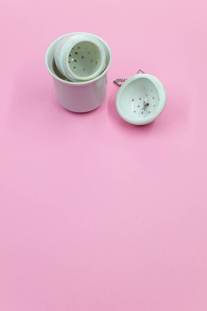 A vertical shot of a white tea strainer with an infuser isolated on a pink background - Foto, Imagem