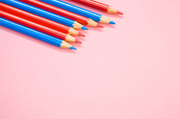 A high angle shot fo red and blue pencils on a pink surface - Photo, image