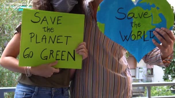 Открытый портрет кавказской пары активистов с плакатом Save the Planet, World ecology - демонстрация протеста и флешмоб на балконе во время карантинного карантина Ковид-19 - Кадры, видео