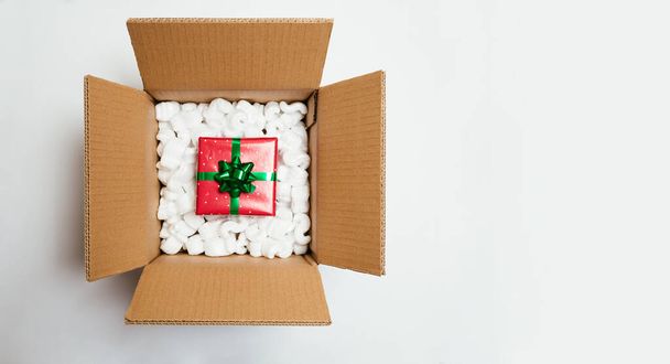 Christmas gift in a cardboard box with foam cushion isolated on white. Christmas home delivery or shipping concept. Top view - Fotoğraf, Görsel