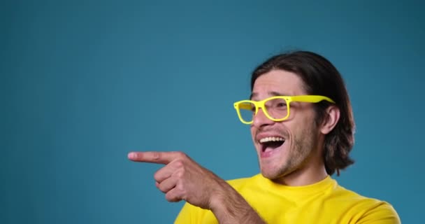 Hombre con gafas amarillas riendo sobre fondo azul - Imágenes, Vídeo