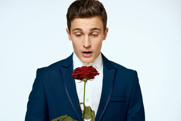 A man in a suit with a rose in his hands a gift date light background - Foto, immagini