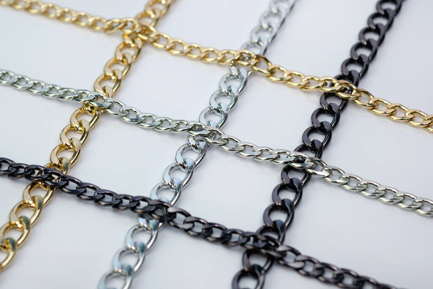 Metal chains for decorating bags and clothes. Decorative chains on a white background. Gold, silver and black chain sewing accessories. - Photo, Image