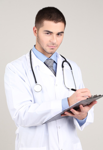Docteur mâle debout avec dossier, sur fond gris
 - Photo, image
