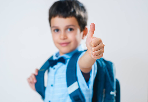 Школьник в рубашке с бабочкой и рюкзаком за спиной показывает большой палец. Сосредоточься. Концептуально. Копирование пространства. - Фото, изображение