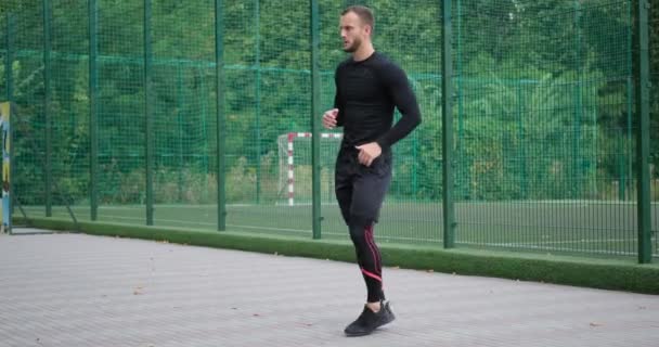 Deportista corriendo en el acto y estirando las piernas - Metraje, vídeo