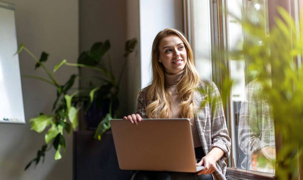 Shot of a young businesswoman with laptop in her office - Foto, afbeelding