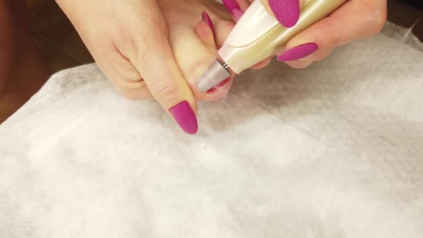 A girl at home does a pedicure, polishes her toenails with a special sanding machine, hardware manicure. - Footage, Video