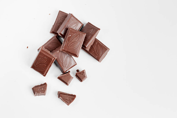 Trozos de chocolate con leche aislados sobre fondo blanco desde la vista superior, cierran una barra de chocolate aislada sobre fondo blanco - Foto, Imagen