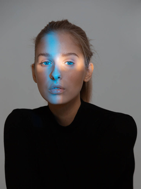 Portrait of elegant young girl with ray of blue light on face looking to camera - Fotografie, Obrázek