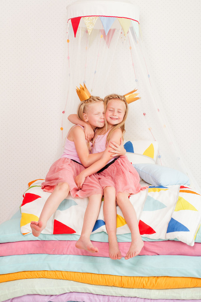Two little girl lying on a pile of mattresses - Foto, afbeelding