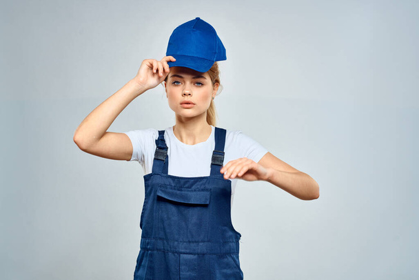 woman in work uniform blue cap service delivery service light background - Φωτογραφία, εικόνα