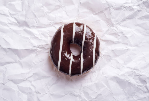 Chocolate donut on crumpled paper - 写真・画像