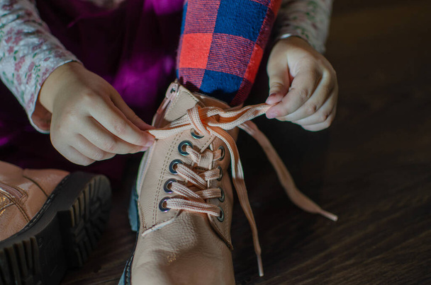 the girl ties the laces on her shoes, in red tights - Foto, Bild