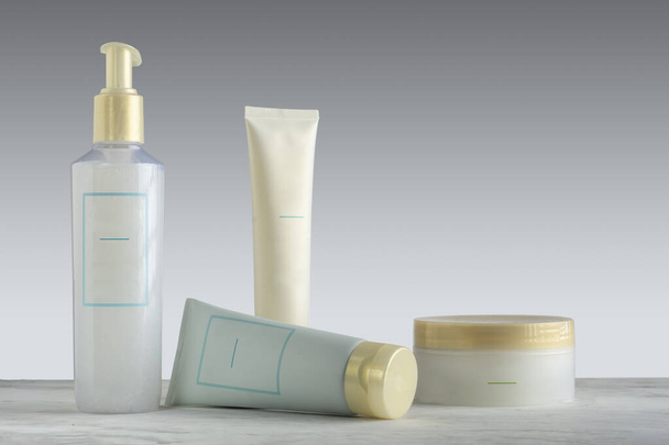 Kit de cremes para cuidados faciais, que inclui vários produtos de cuidados com a pele, em uma base de mármore e fundo gradiente. - Foto, Imagem