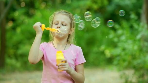 Porträt eines lustigen kleinen Mädchens, das Seifenblasen pustet. Glückliche unbeschwerte Kindheit. Zeitlupe 100 fps. - Filmmaterial, Video