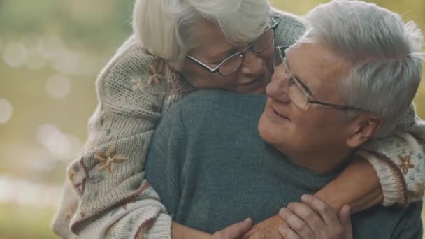 Happy old couple hugging in park. Senior man flirting with elderly woman. Romance at old age dancing on autumn day - Footage, Video