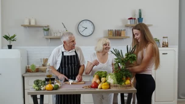 Coppia anziana in cucina che riceve verdure da nipote. Alimenti crudi dieta sana - Filmati, video