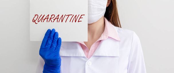 word QUARANTINE on paper in hands of doctor in protective gloves over white background. medical lockdown concept, banner - Foto, Imagem