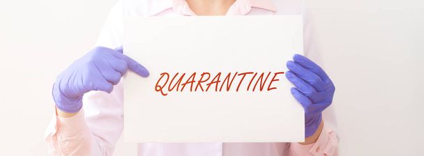 word QUARANTINE on paper in hands of doctor in protective gloves over white background. medical lockdown concept, banner - Foto, Bild