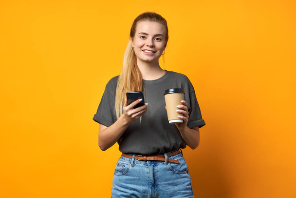 Photo of cheerful positive curly pretty sweet girlfriend holding mug of coffee smiling toothily isolated over vivid color background. - 写真・画像