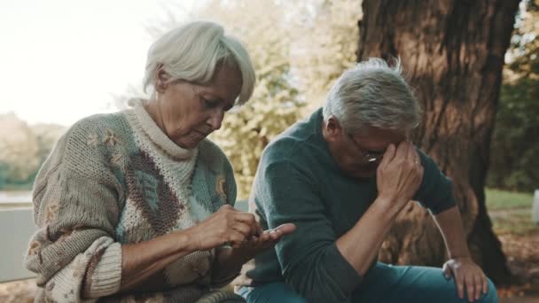 Ein älteres besorgtes Paar sitzt verzweifelt auf der Bank. Frau zählt letzte Münzen - Filmmaterial, Video