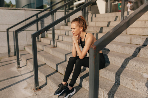 Full-lenght portrait of fit pretty young woman. Portrait of fit and sporty young woman doing stretching in city. - 写真・画像