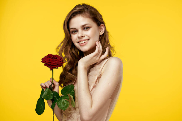 Романтична жінка в вечірній сукні з червоною трояндою на жовтому тлі обрізаний портрет
 - Фото, зображення