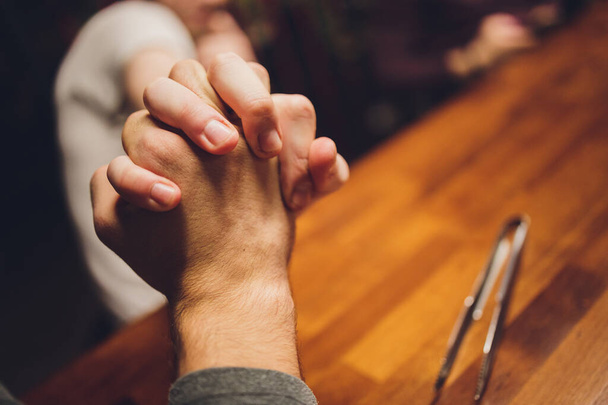 Close up male and female holding hands over table. - 写真・画像